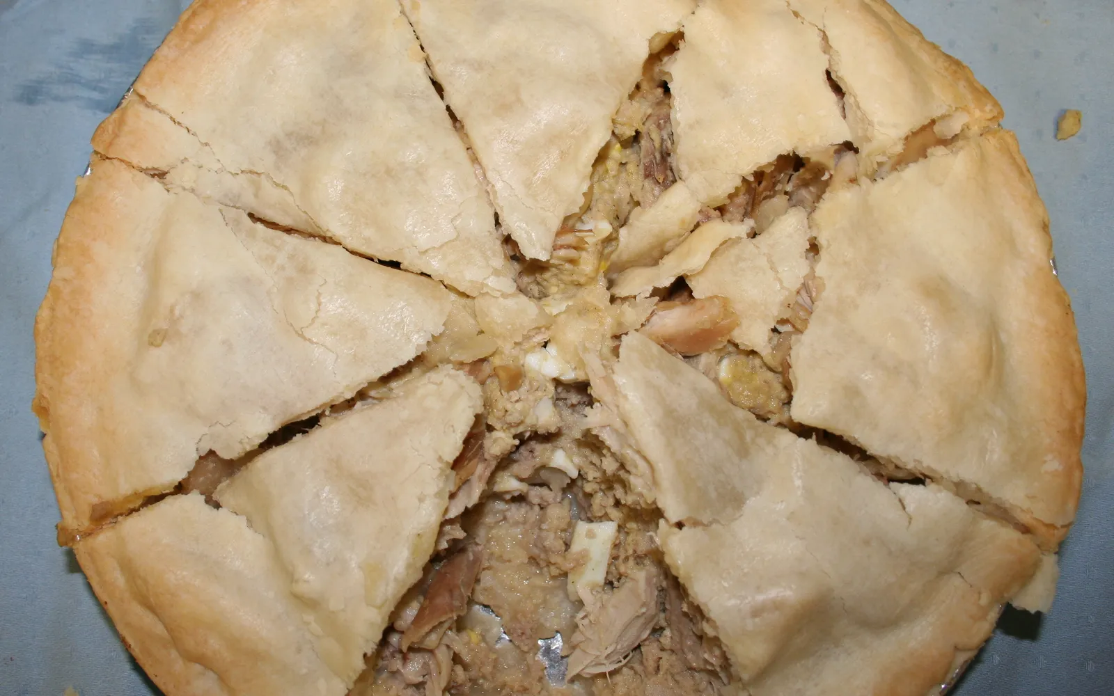 A Tasmanian scallop pie — a small round pie with golden pastry, cut open to show the thick white creamy scallop filling inside