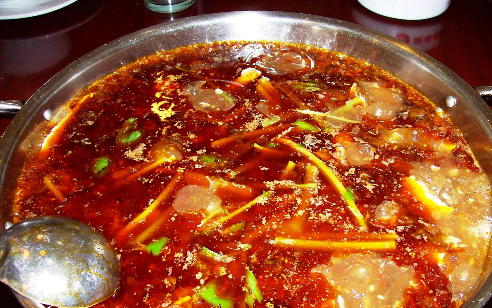 Chongqing grilled fish in an iron tray surrounded by spicy mala broth and bright fresh vegetables