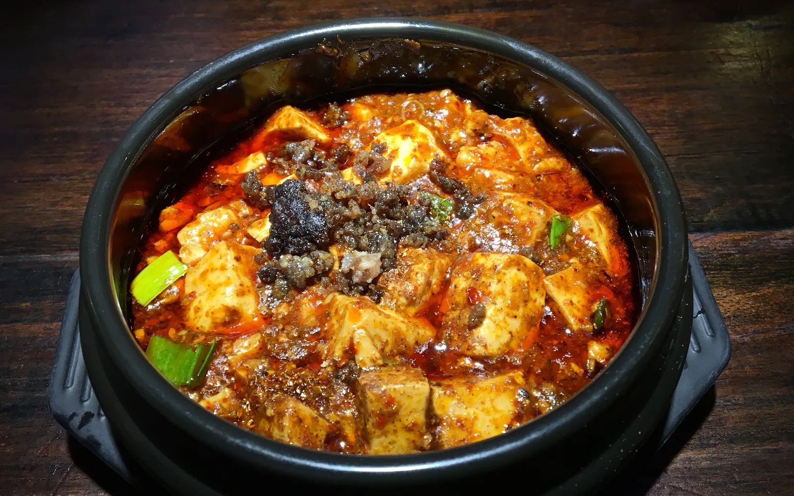 A plate of Chongqing mapo tofu, deep red and full of mala flavour, with minced meat and spring onion