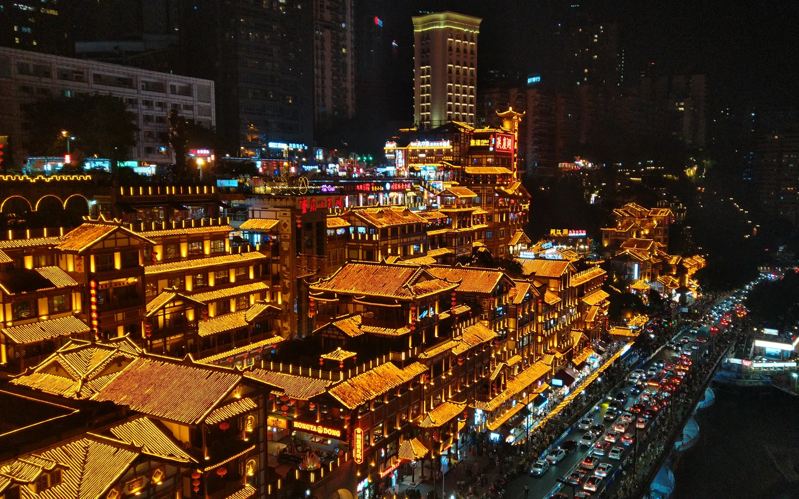 The brightly lit wooden Hongyadong complex at night along the Jialing River in Chongqing