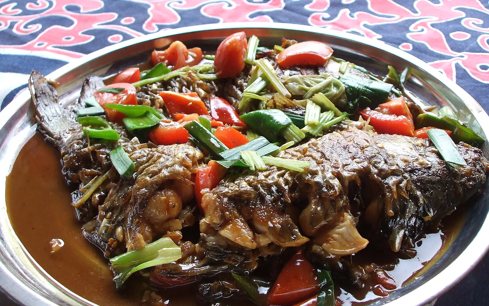 Yangshuo beer fish in a clay pot, fresh carp fried until crisp then braised with beer, tomato, chili and garlic in an appetizing orange-red sauce
