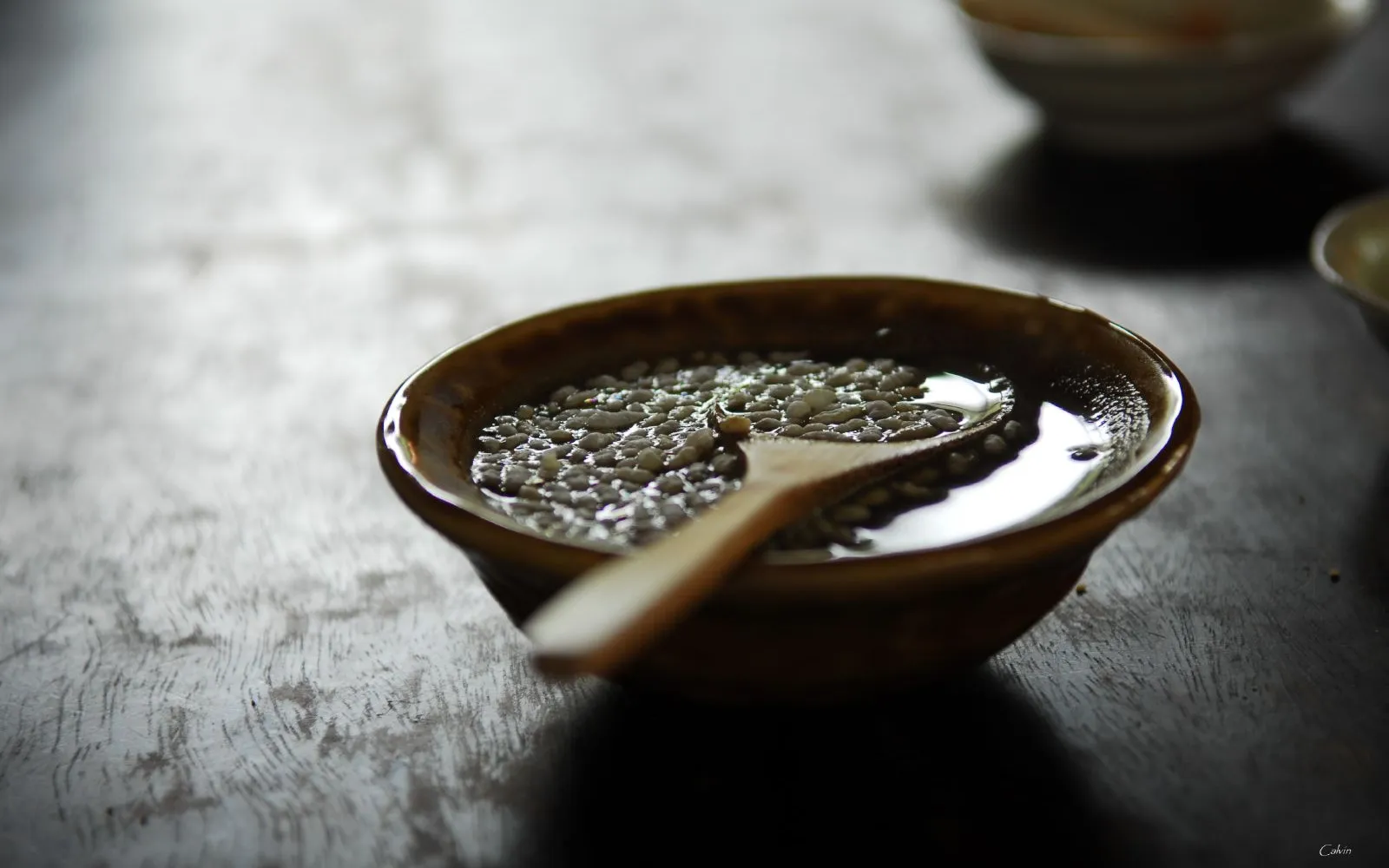 A cup of dark-brown Guangxi oil tea served with crispy puffed rice, peanuts, spring onion and pickled radish