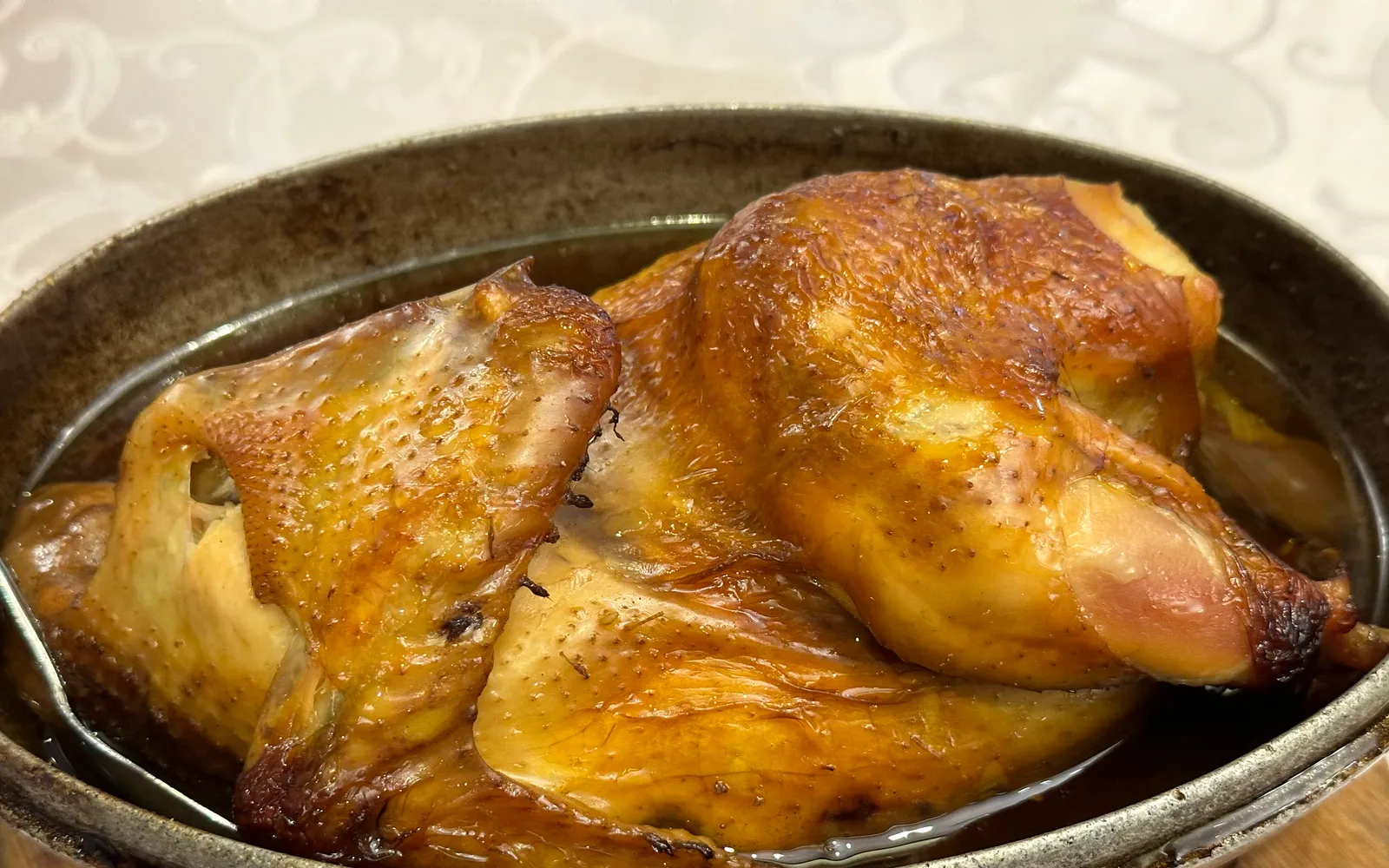 Chicken wrapped in lotus leaf and clay being cracked open at the table, fragrant steam rising over tender, juicy meat