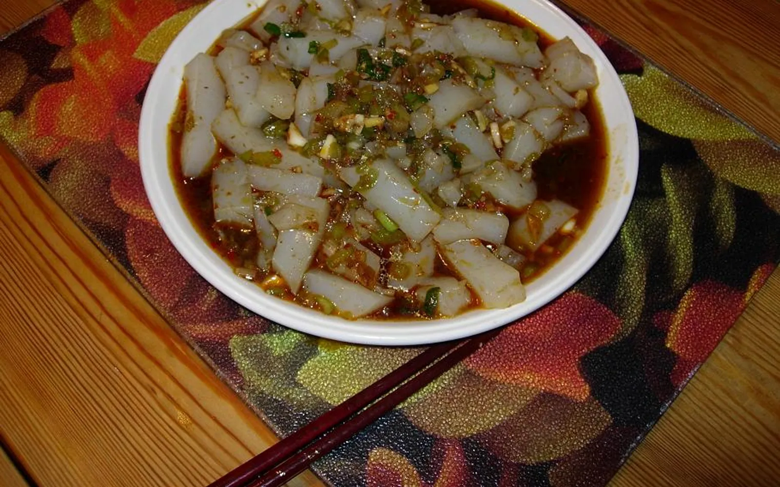 A bowl of golden-yellow chickpea jelly topped with sour chili sauce, Lijiang, Yunnan