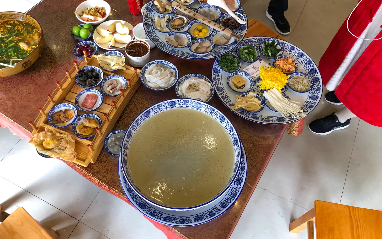 A large bowl of crossing-the-bridge noodles with an array of side ingredients, Yunnan