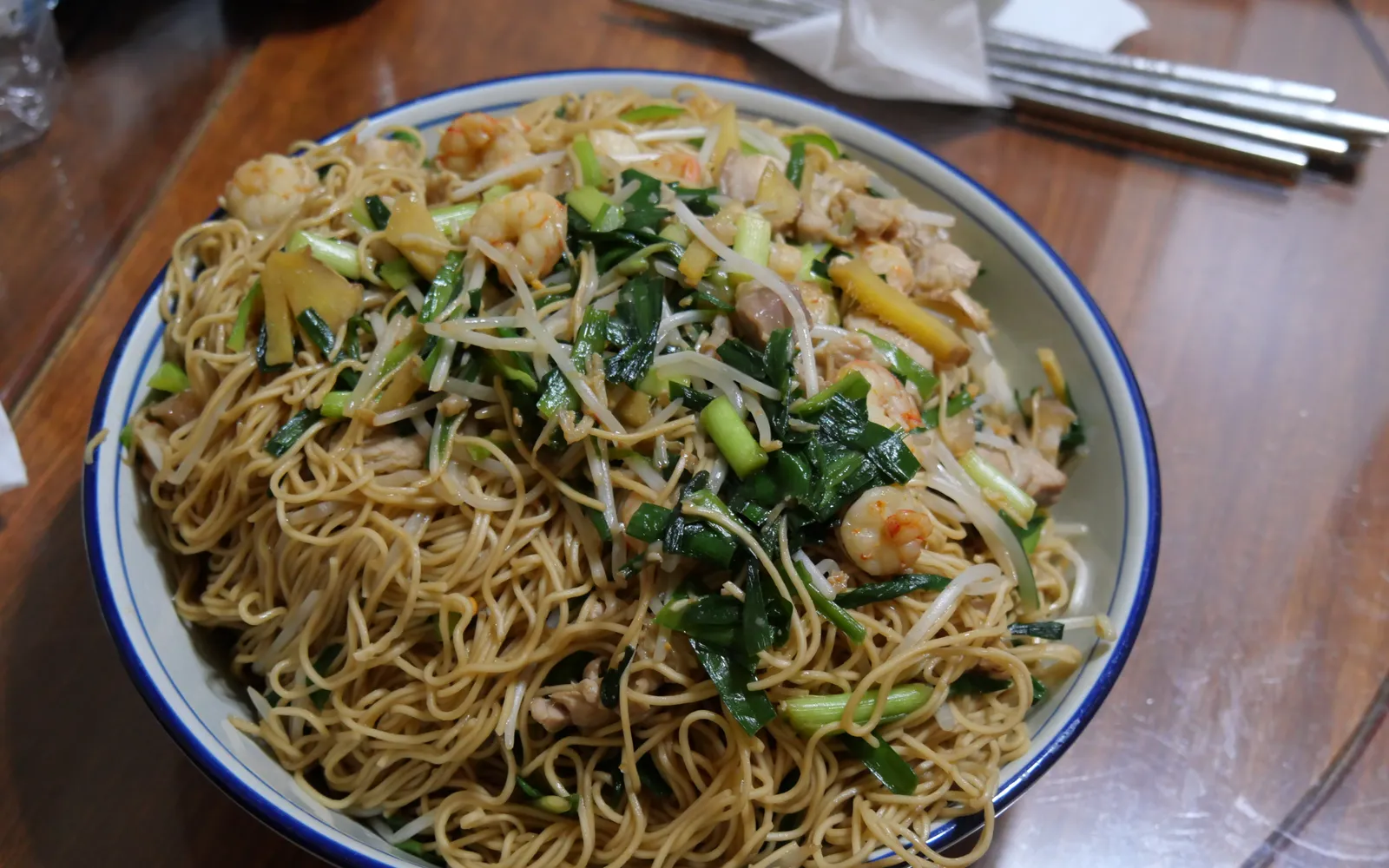 Tianjin-style fried noodles in a hot wok — wheat noodles stir-fried with minced pork, bean sprouts, onion, and dark soy bean paste, deep brown and glossy