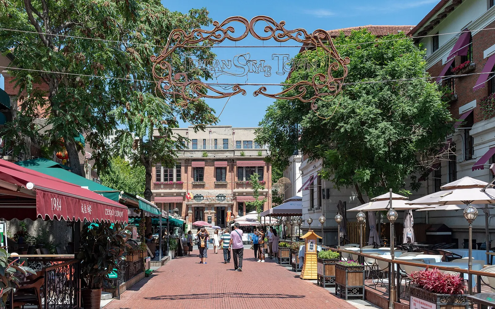 Tianjin's Italian concession street: early 20th-century golden-yellow Italian buildings line a wide avenue, with statues and fountains in the central garden