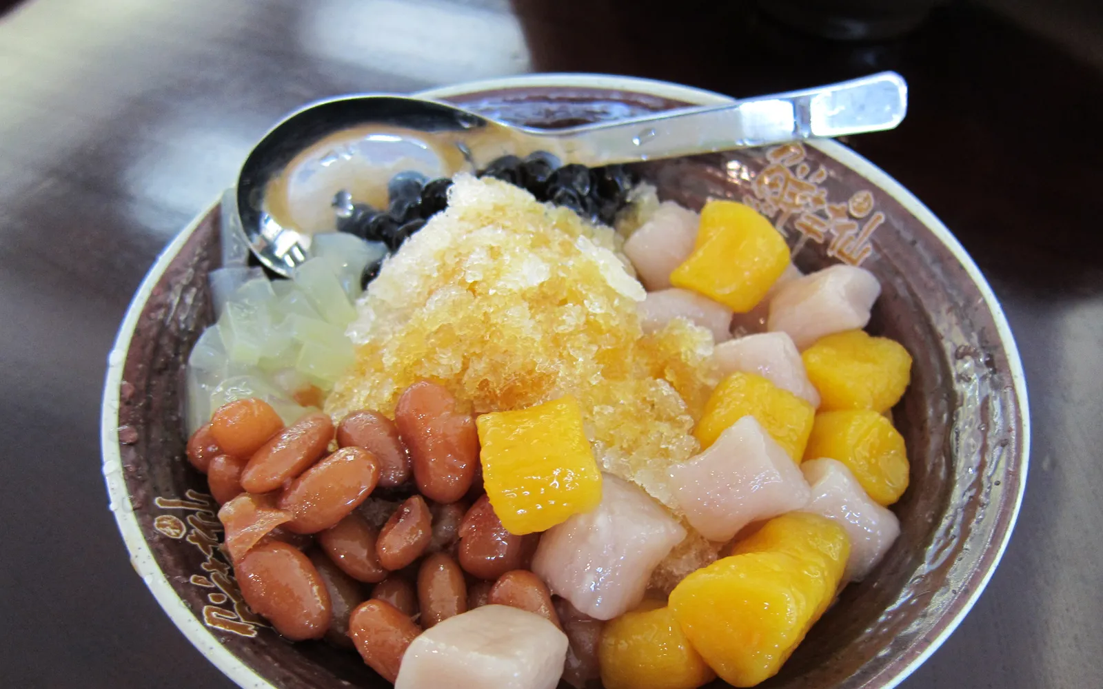 A bowl of Xiamen taro balls — purple and white balls floating in pale-yellow ginger syrup, topped with warm fragrant soy milk