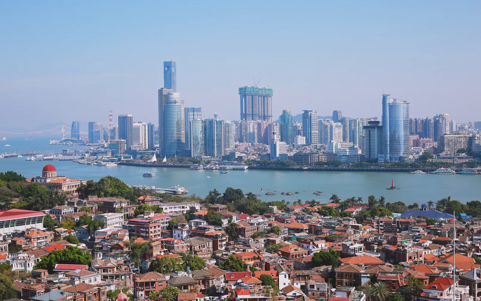 A narrow lane on Gulangyu Island flanked by pastel-coloured European colonial villas and large banyan trees, quiet and car-free