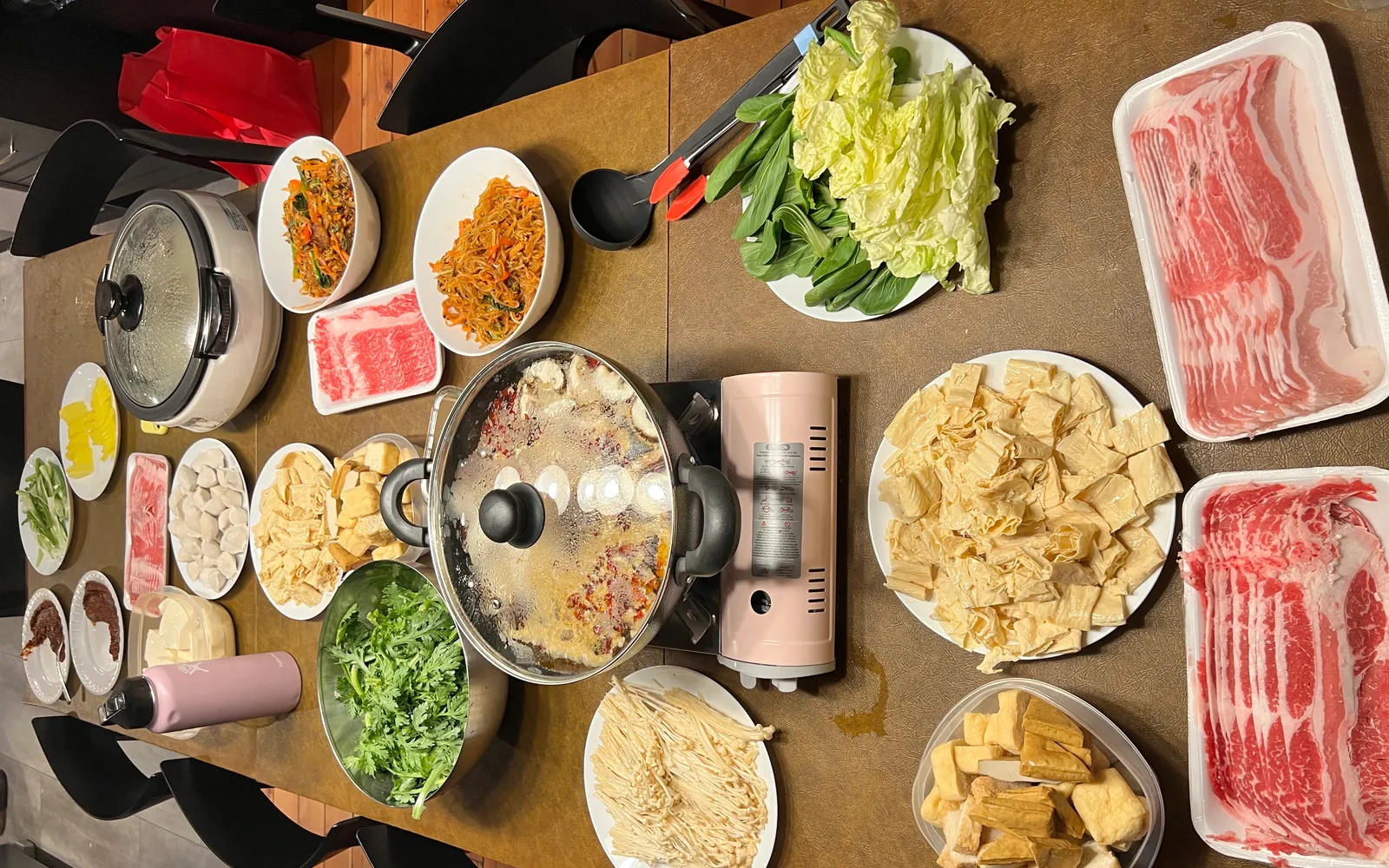 A Henan hot pot with milky-white bone broth boiling in an antique copper pot, surrounded by paper-thin lamb slices, beef, winter vegetables, and tofu