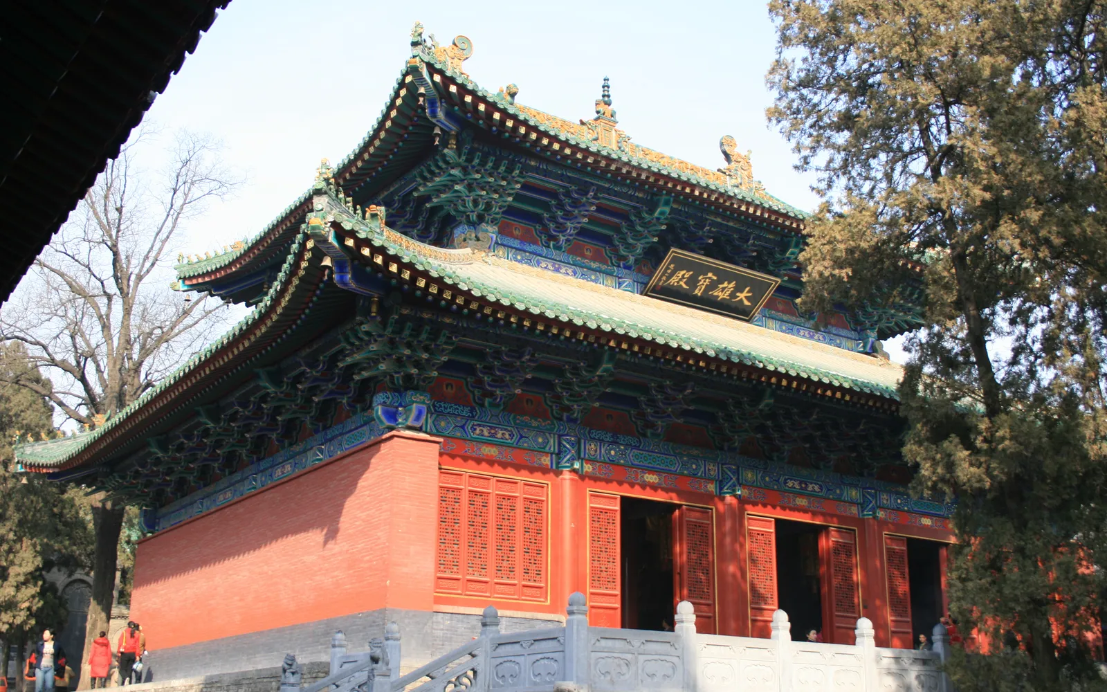 The main gate of Shaolin Monastery at the foot of Mount Song — a red bell tower rises against pine forest and rocky peaks in the morning mist