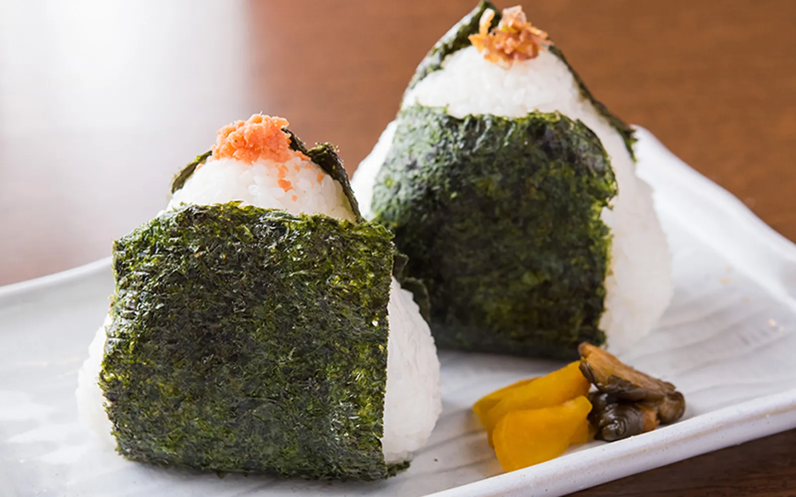 A giant fist-sized round onigiri wrapped in nori seaweed, resting on a paper sheet