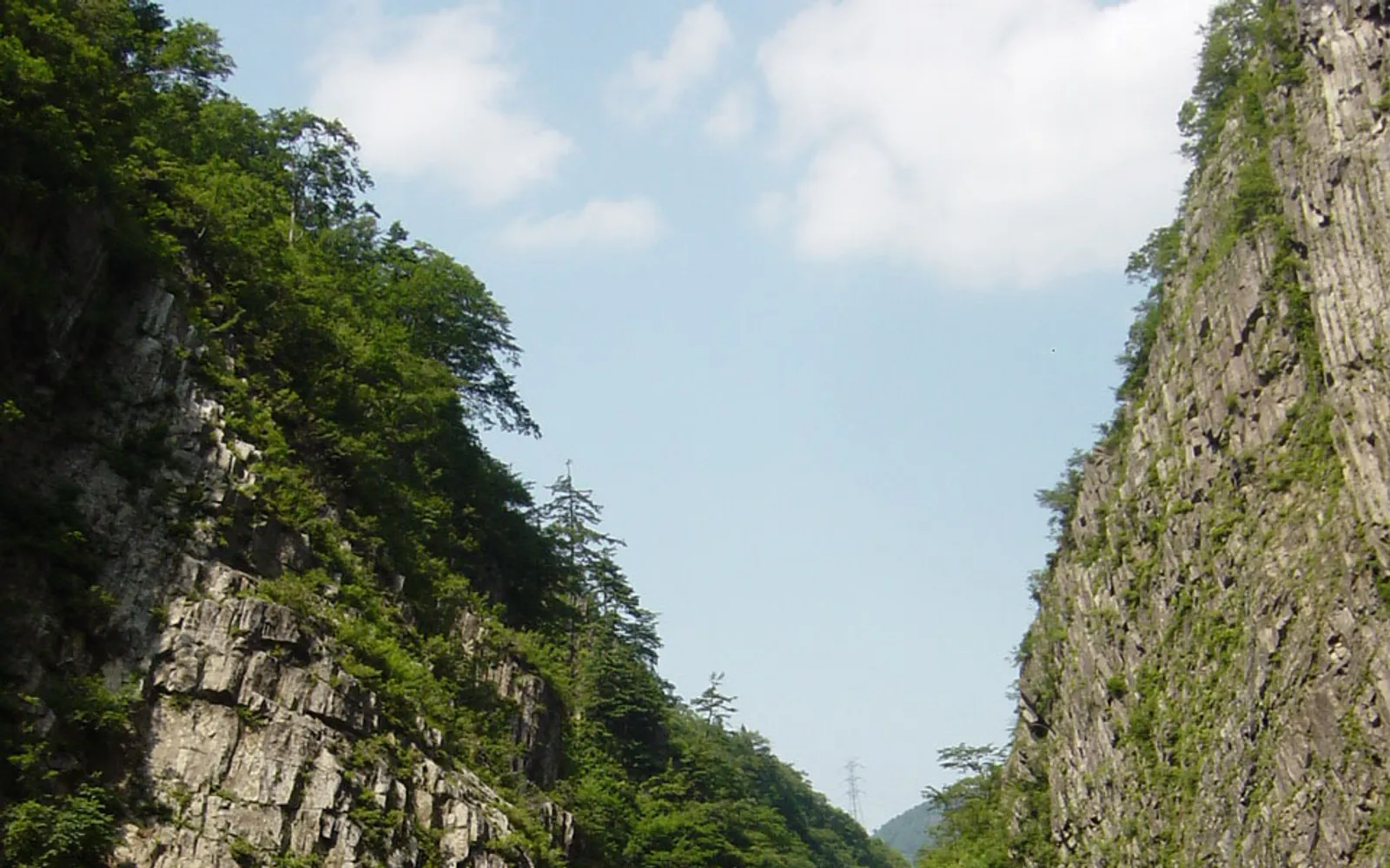 The entrance to the Tunnel of Light at Kiyotsu Gorge, with a waterfall and red cliff face beyond