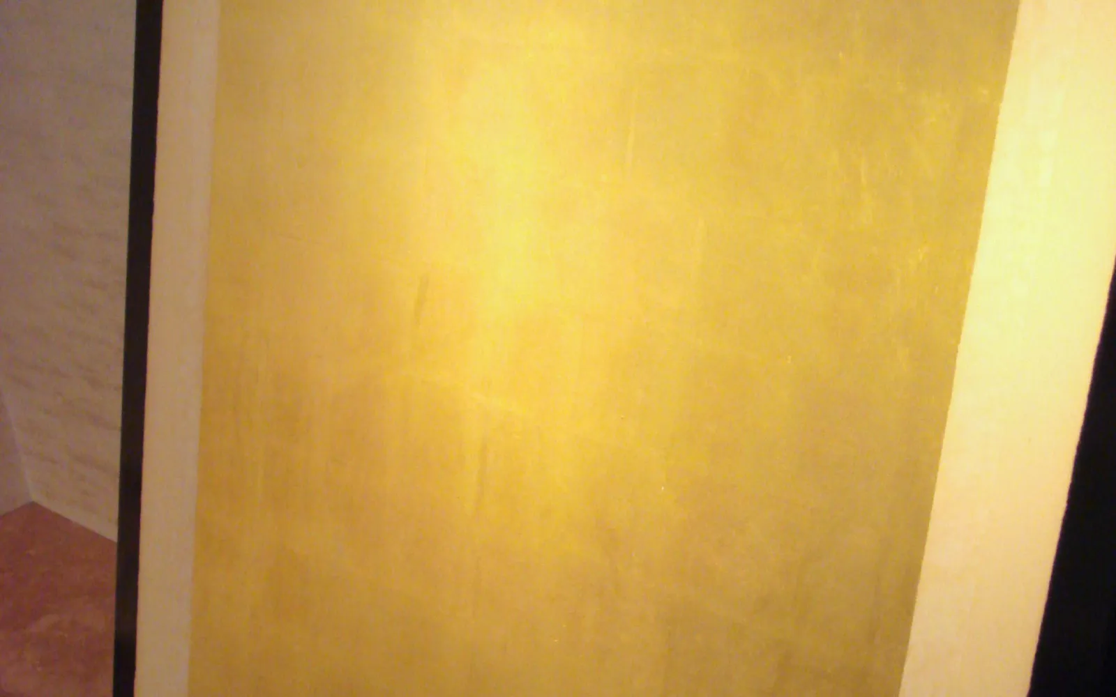 A soft serve cone wrapped in a large sheet of pure edible gold leaf, gleaming and reflective