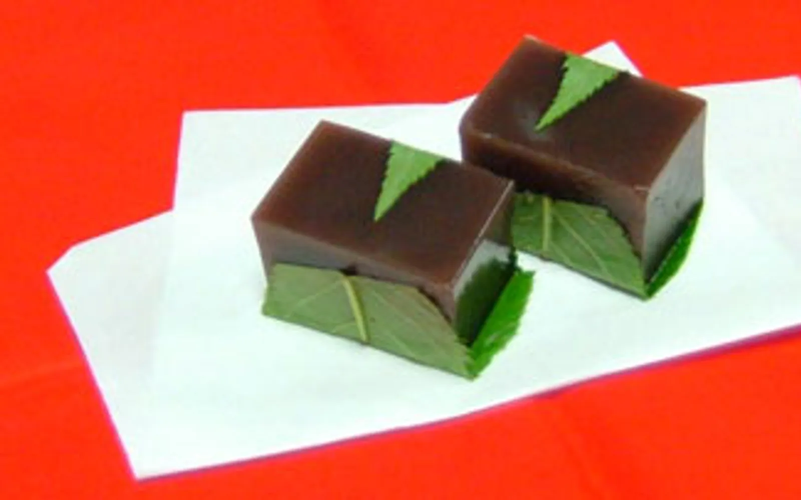 Imo yokan — golden-orange squares of firm sweet potato wagashi resting on bamboo paper