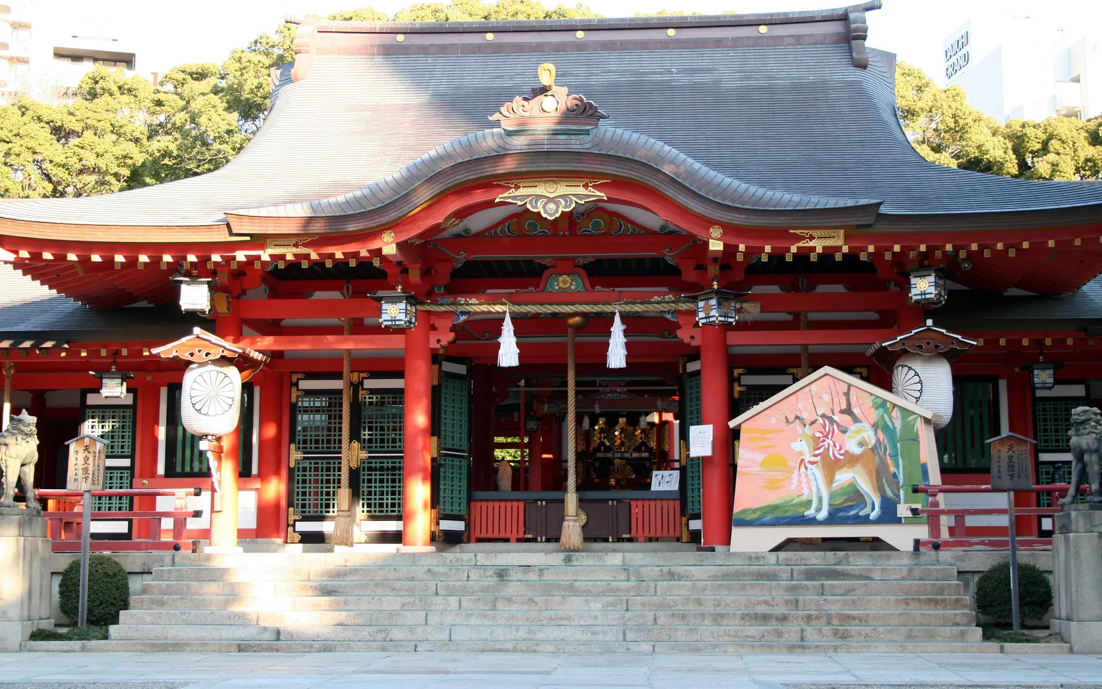 The red torii gate and main hall of Ikuta Shrine surrounded by ancient trees in central Kobe