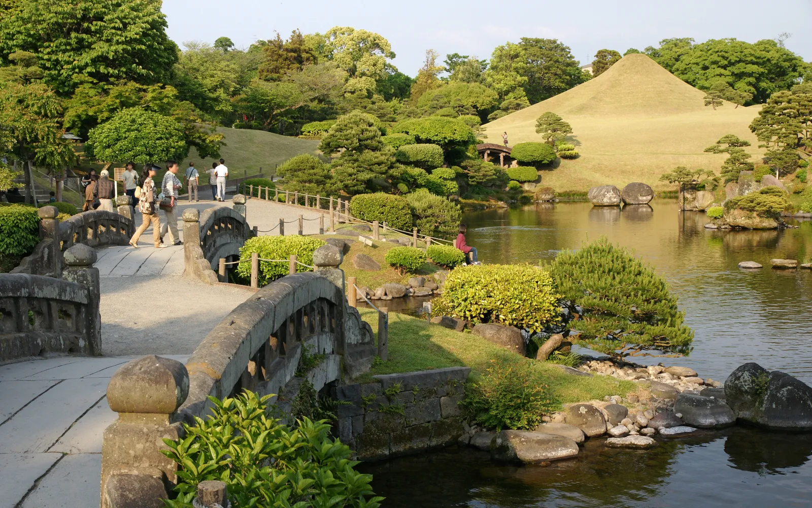 A Japanese garden with a sculpted hill replicating Mount Fuji reflected in a clear pond