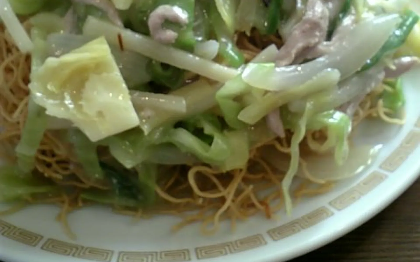 A plate of Sara Udon — crispy fried thin noodles topped with a thick sauce of seafood and colourful vegetables