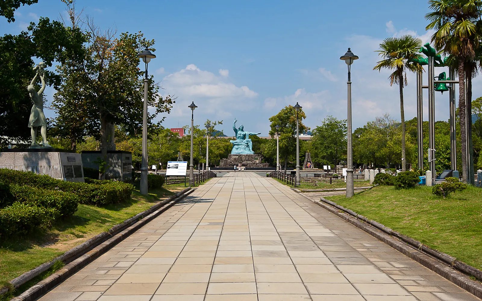 The towering bronze Peace Statue in Nagasaki Peace Park against a clear blue sky
