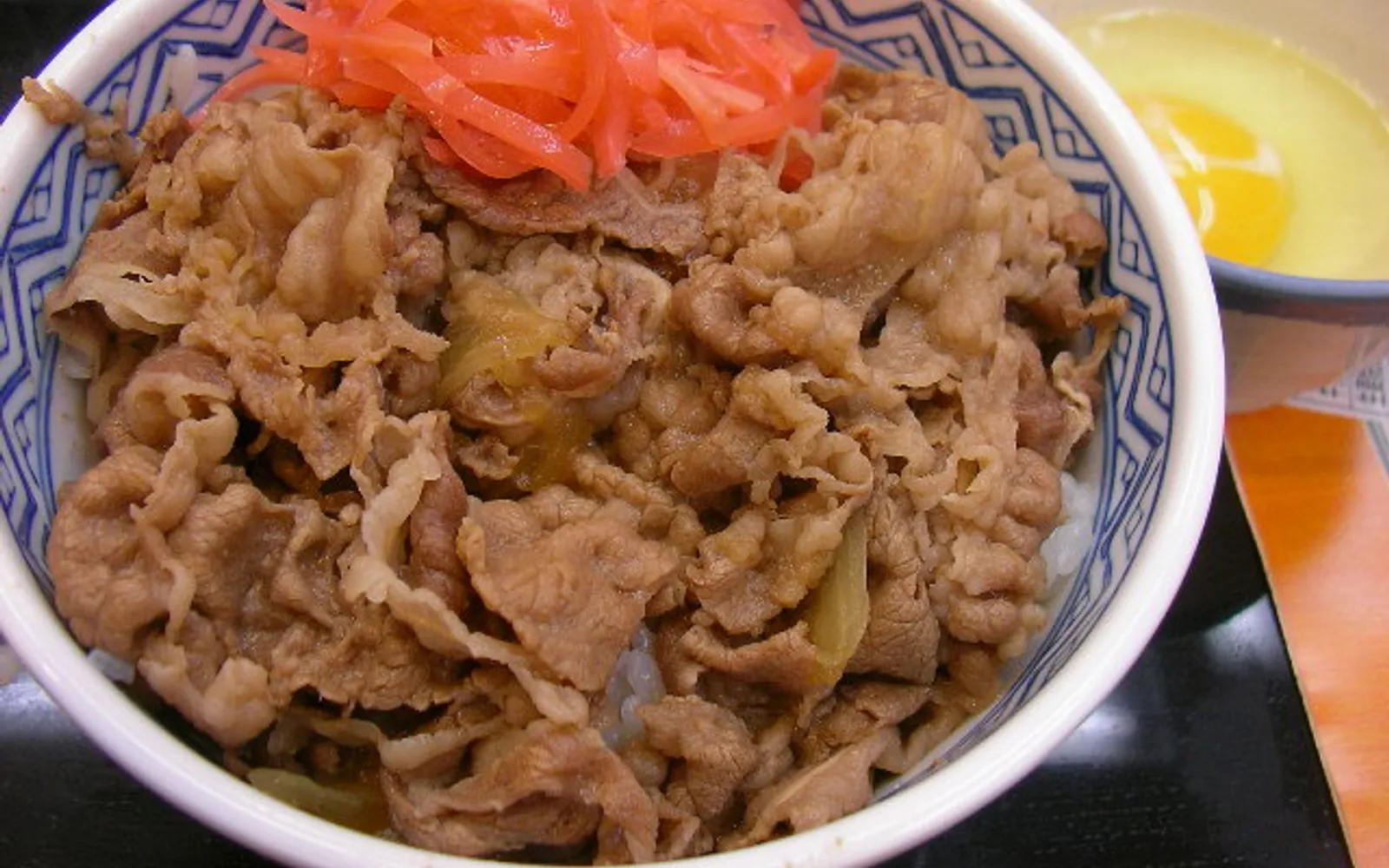 A large Kaisen-don seafood bowl with scallops, uni, salmon, and bright orange ikura arranged over white rice