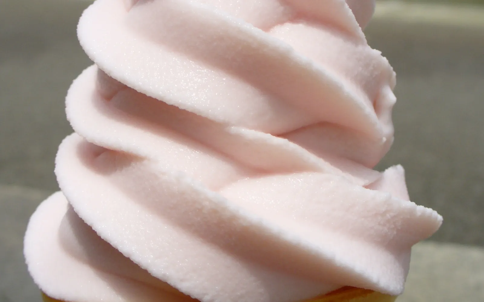 A tall swirl of creamy white soft-serve ice cream on a crisp cone, Niseko snow blurred in the background