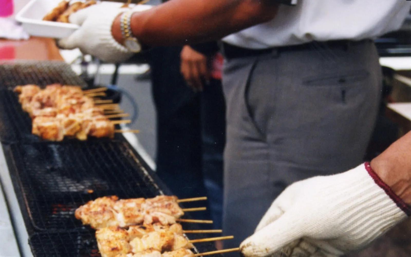 Skewers of charcoal-grilled yakitori chicken lined up on a grill, smoke drifting through a warm izakaya interior