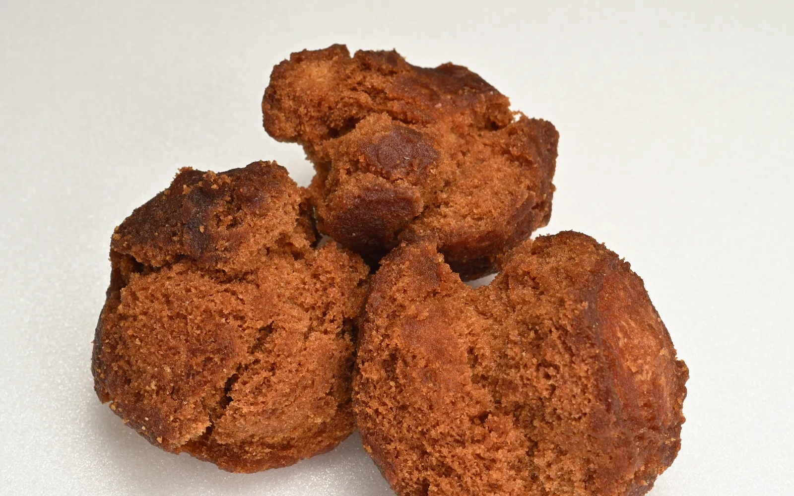 Sata andagi — golden-brown round Okinawan fried doughnuts with naturally cracked surfaces, served in a paper tray