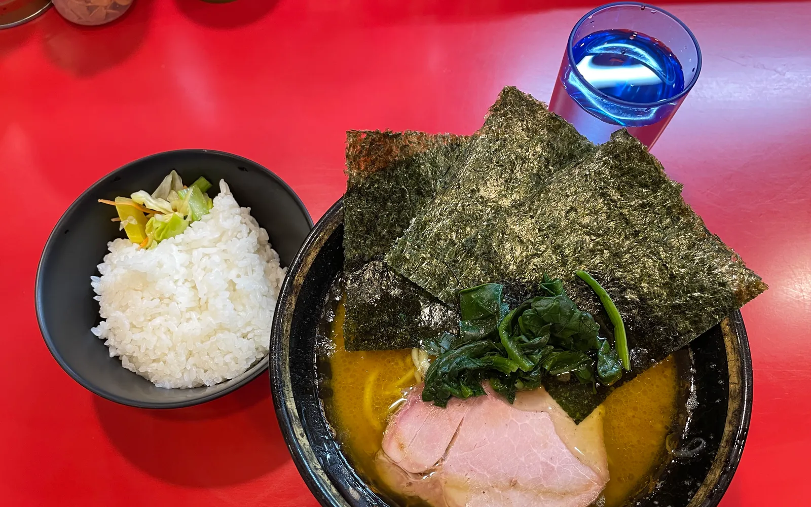 A bowl of Iekei ramen with rich golden-brown broth, three sheets of nori, and thick chashu pork