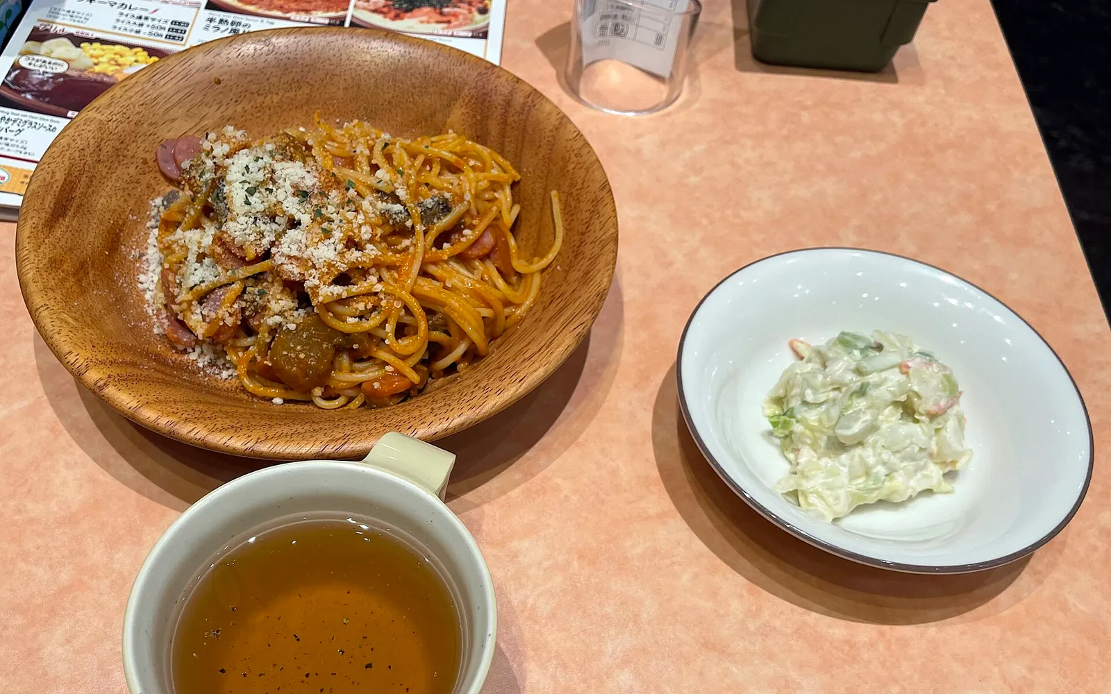 A plate of orange-red Napolitan pasta tossed in tomato sauce with sausage and green peppers
