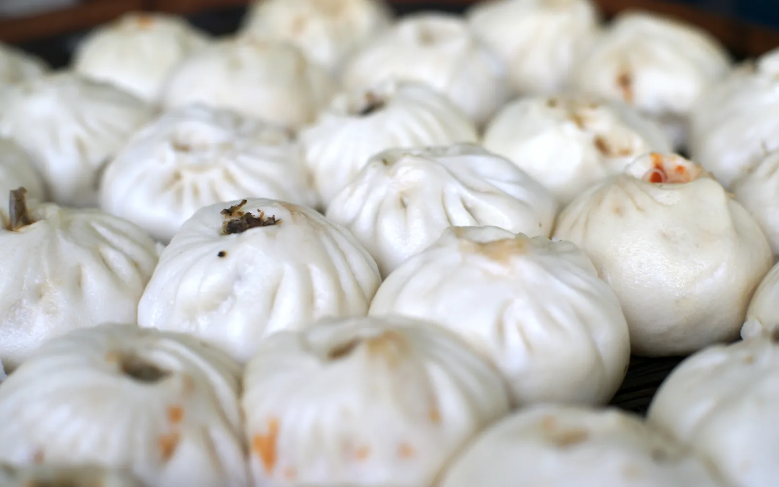 Plump white steamed buns sending up steam outside a Chinatown stall