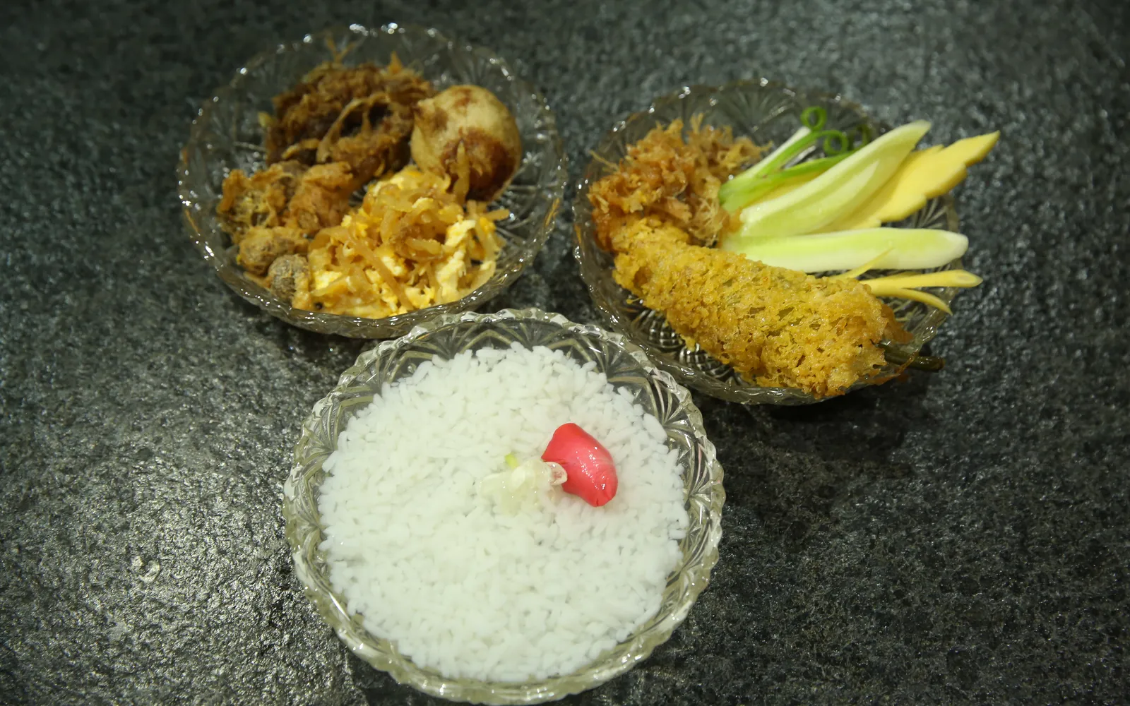 Khao Chae — jasmine-scented rice in a clear glass bowl of flower-infused water, served with an array of colorful accompaniments
