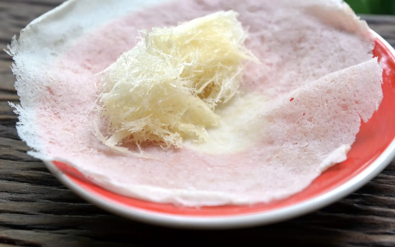 Thin white roti sheets wrapped around delicate, brightly colored sugar threads called sai mai
