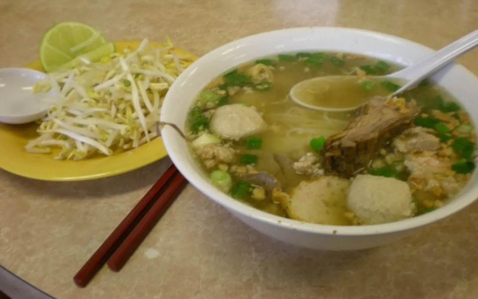 A small clay bowl of nam tok boat noodles — dark intense broth with pork blood and offal, served in the original canal-boat style