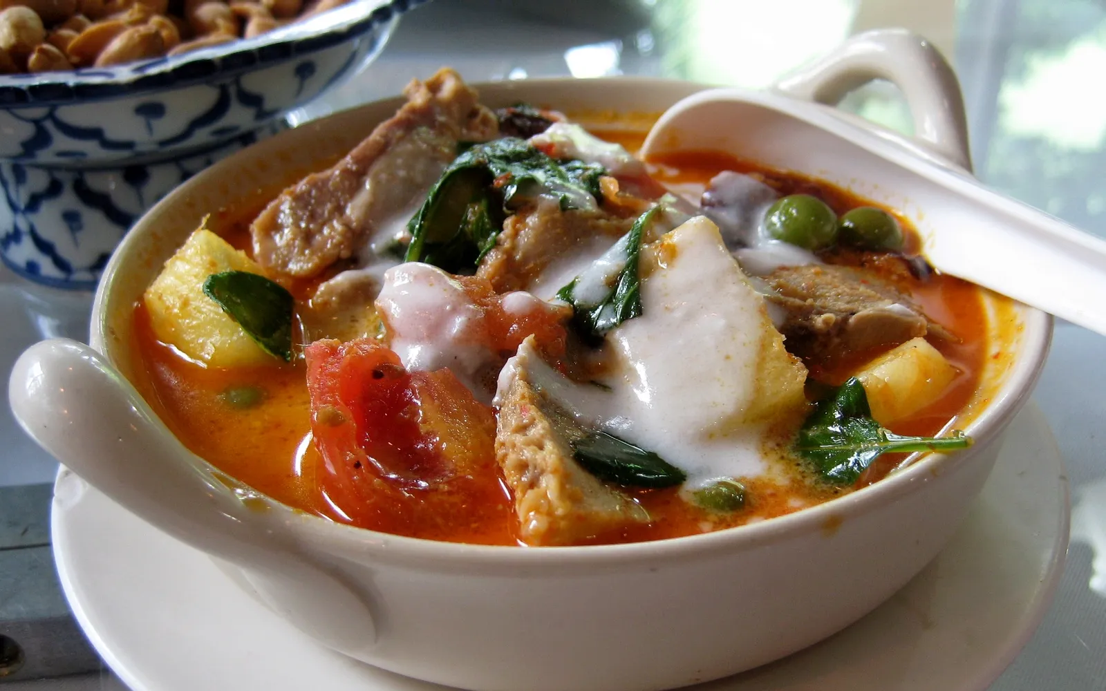Green curry chicken with thick coconut milk over steamed rice — deep green broth fragrant with herbs and Thai eggplant