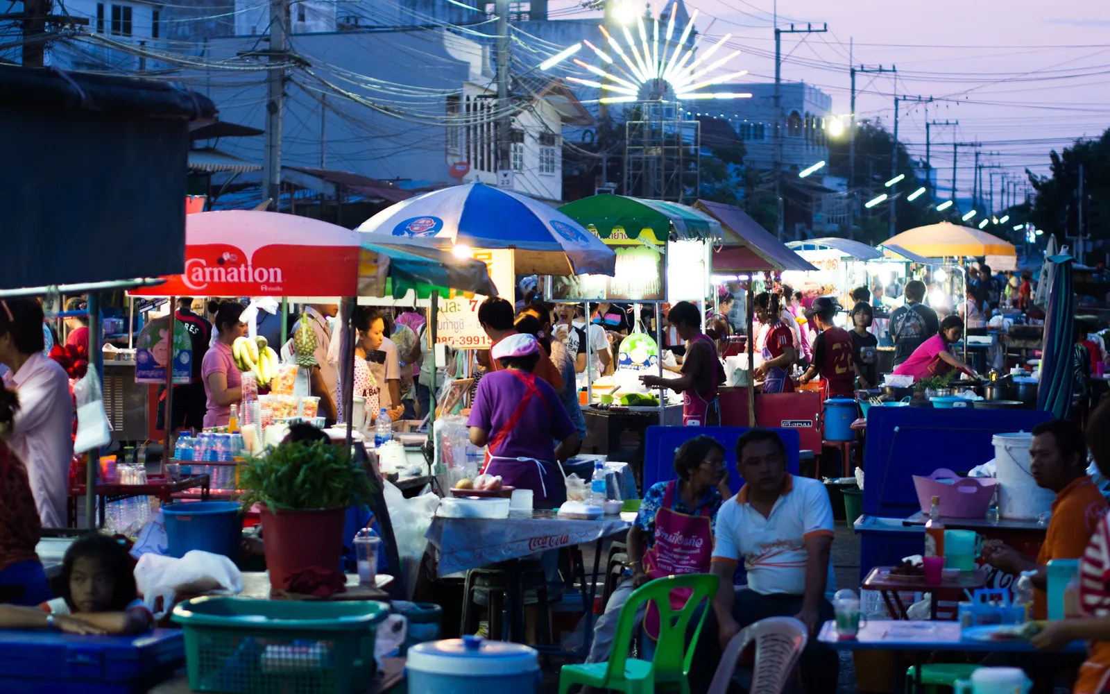 Bangkok street-food cart at night — a charcoal grill loaded with skewers, fragrant smoke drifting through the dark