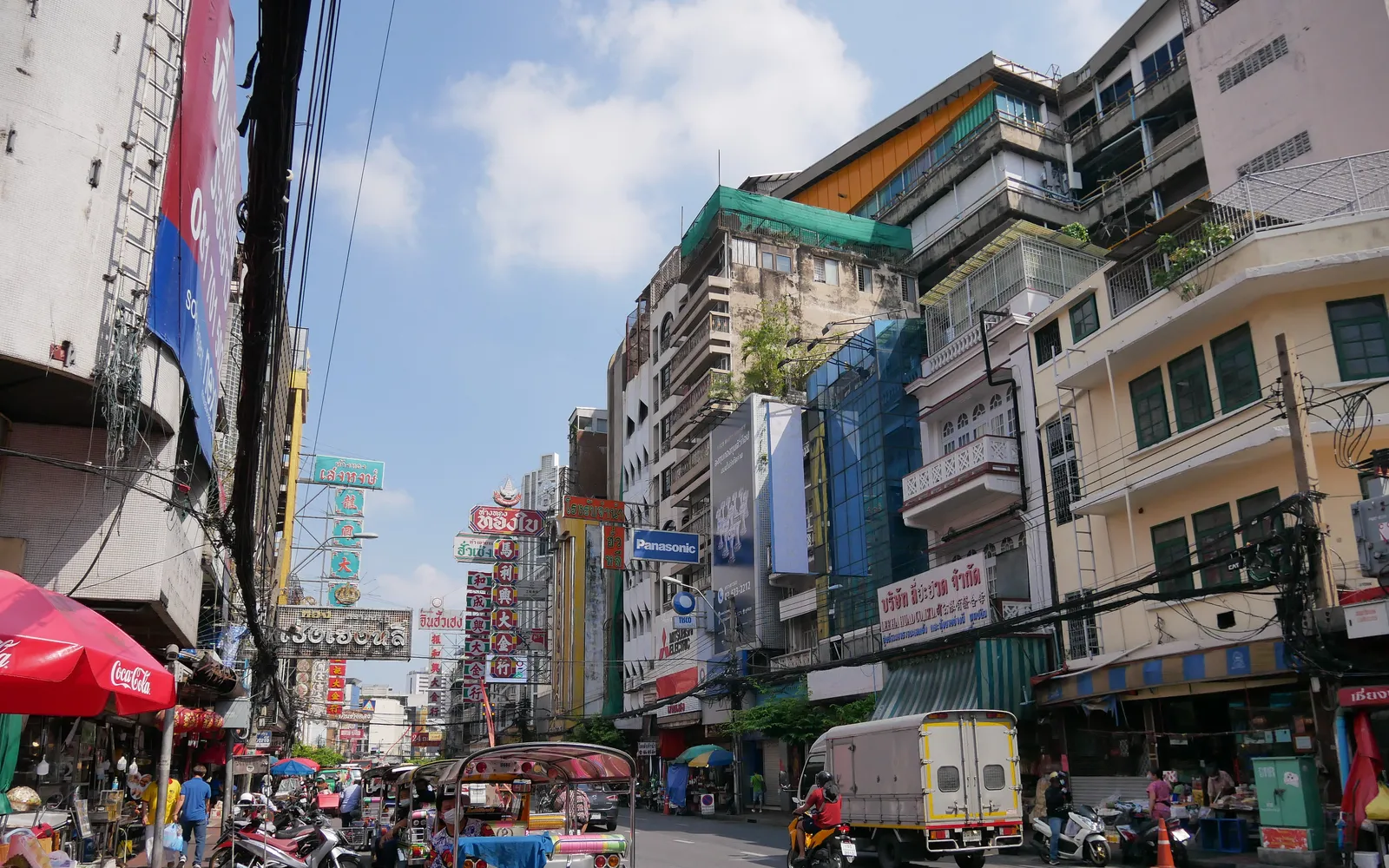 Yaowarat Road in Bangkok at night, red and gold Chinese signs lining both sides of the street, busy with traffic and people