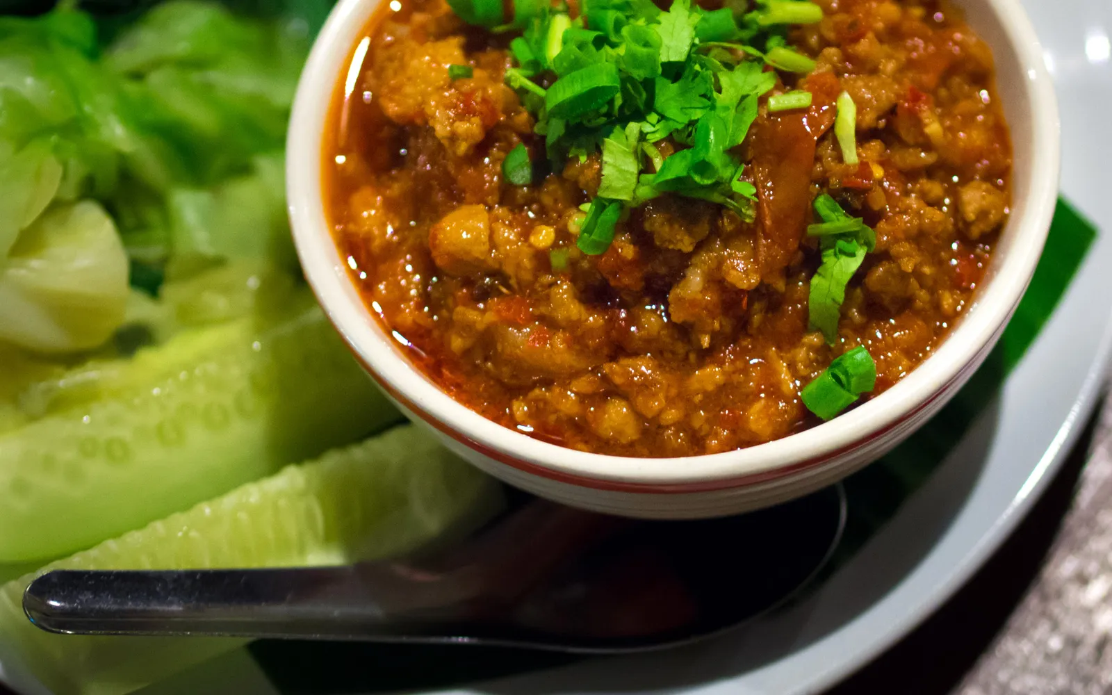 Lanna nam phrik ong in a clay bowl — red-orange minced pork and tomato chili dip served with fresh vegetables and crispy pork rinds
