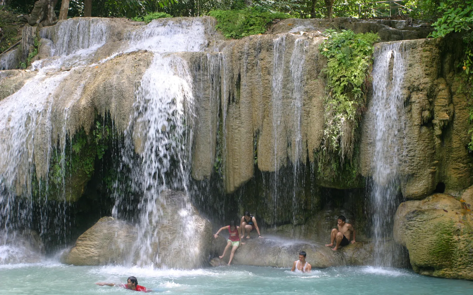 The 7th tier of Erawan Falls — translucent emerald water surrounded by lush green forest