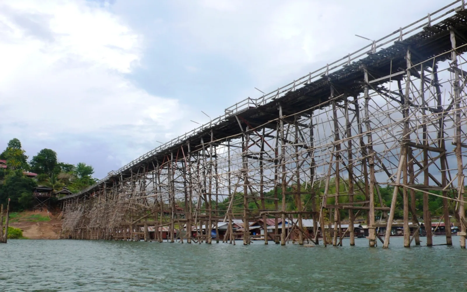 The long wooden Mon Bridge stretching across the Vajiralongkorn Reservoir at dawn