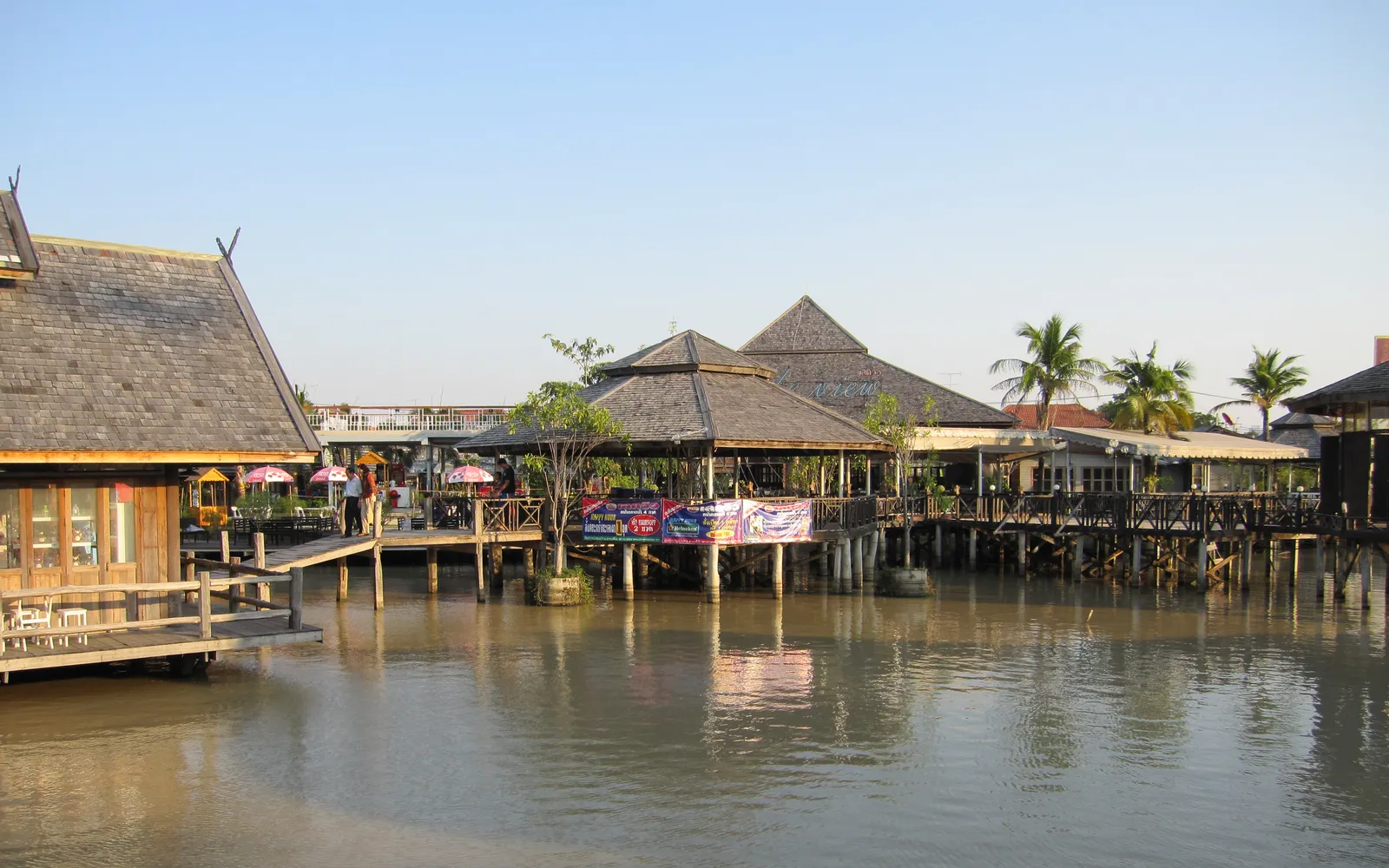 Pattaya Four Regions Floating Market — old wooden boats on still canals, vendors in regional Thai dress selling food and crafts from all four parts of the country