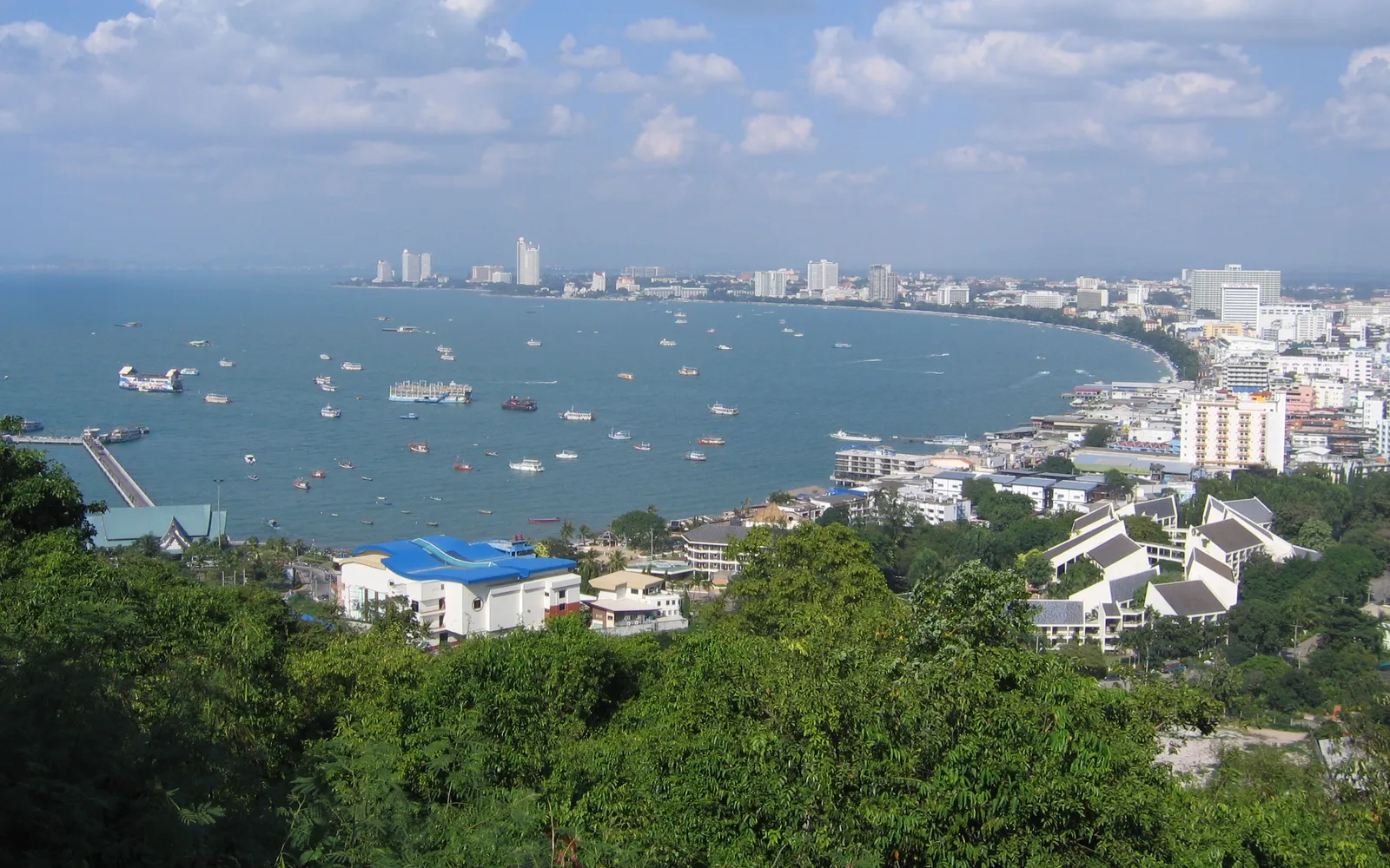 Koh Larn's white-sand beach near Pattaya — emerald-green water clear enough for coral viewing, with swimmers and snorkelers in the shallows